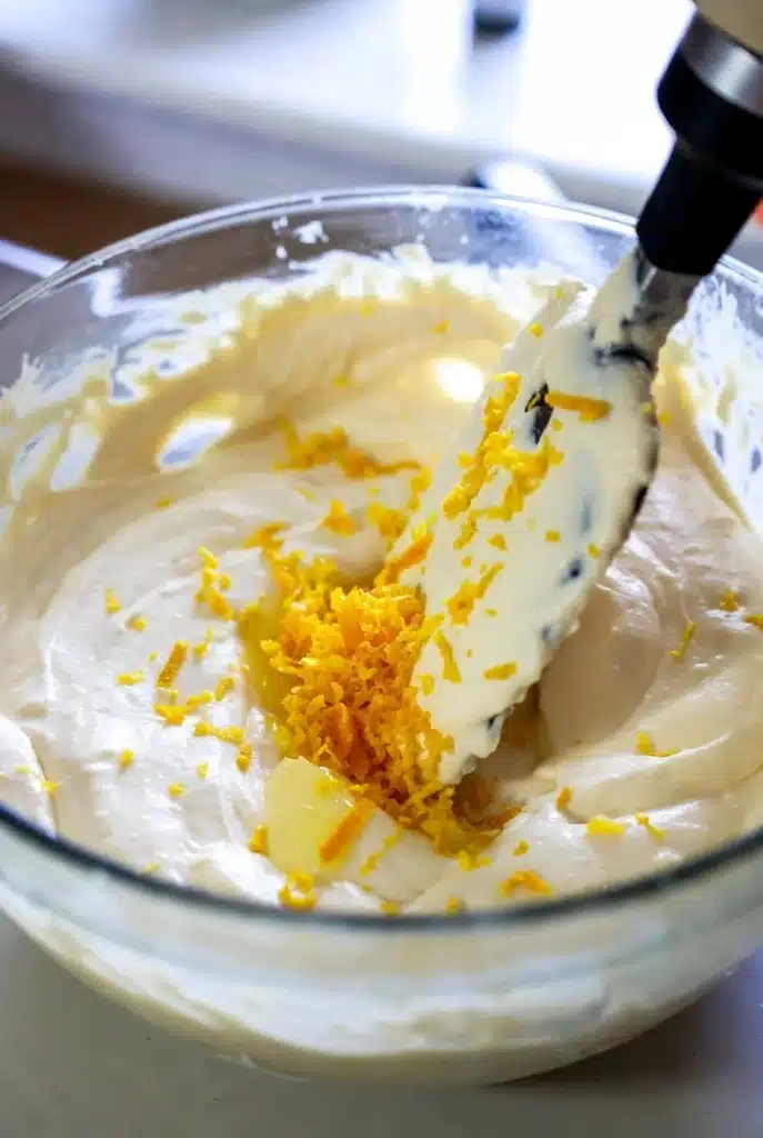 creamy batter being mixed with citrus zest in a bowl