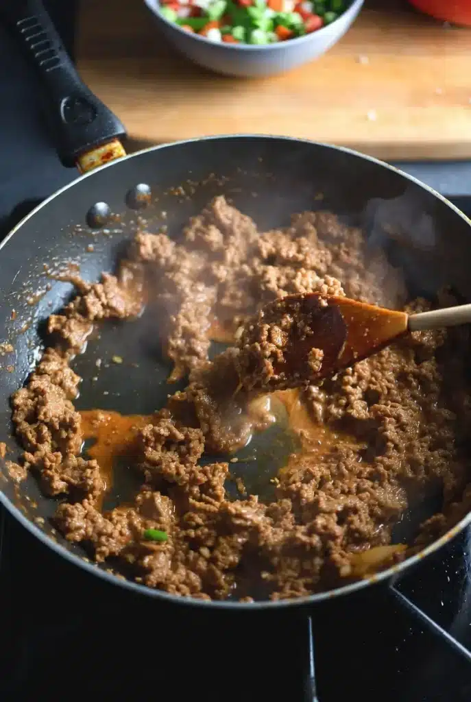Homemade Mexican Pizza Recipe – Easy & Delicious 9 ground beef cooking with seasoning in a skillet