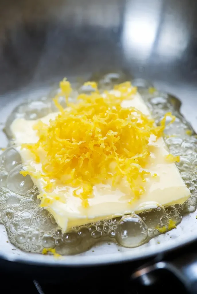 pasta being tossed with melted cheese in a pan