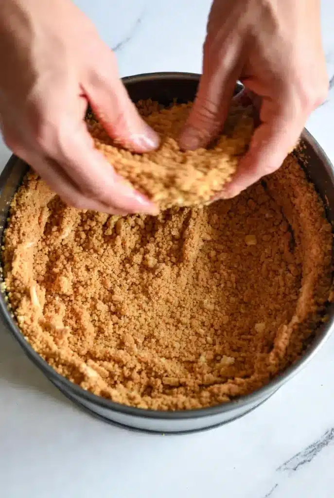 pressing graham cracker crust into a springform pan
