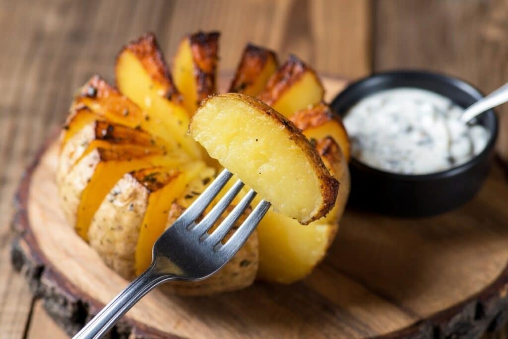 crispy baked potato opened like a flower with dipping sauce