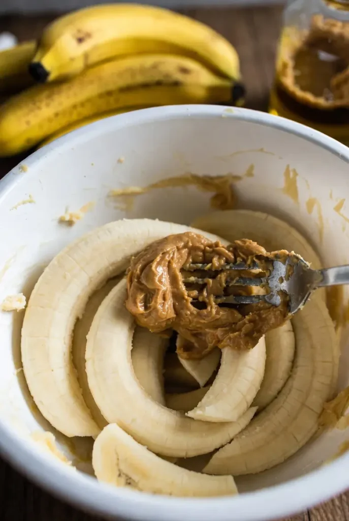 ripe bananas mashed with creamy peanut butter in a bowl
