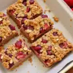 Fresh Almond Butter & Strawberry Oatmeal Bars stacked on rustic wooden board