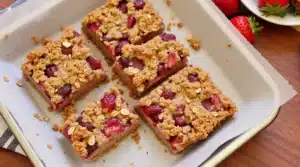 Fresh Almond Butter & Strawberry Oatmeal Bars stacked on rustic wooden board